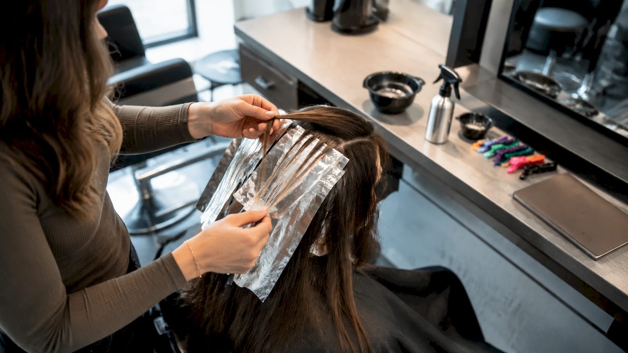 Hairdresser’s hands applying foil highlights on hair