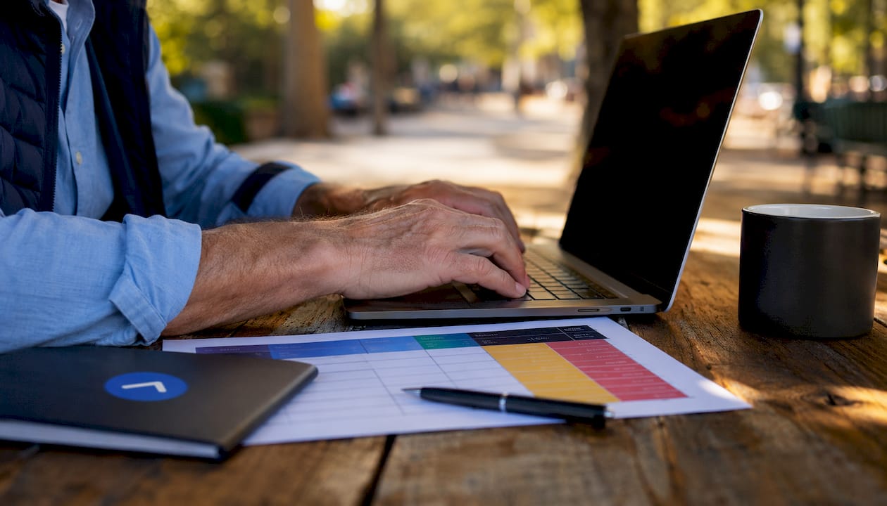 Hands typing on laptop with negotiation worksheet