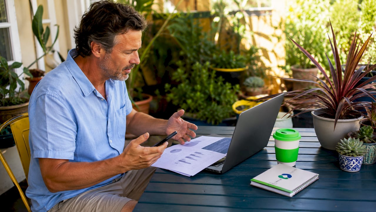 Hands using laptop and phone to compare cashback apps
