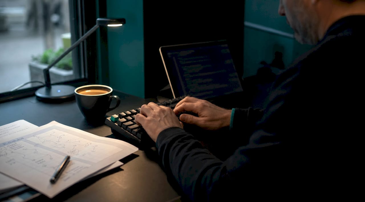 Hands typing near hypothesis document in office