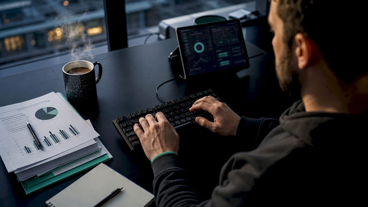 Hands typing financial loss data at workstation