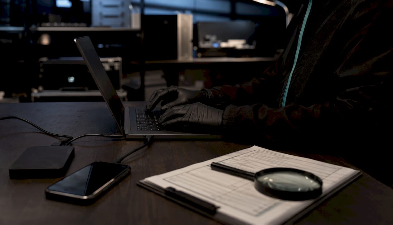 Hands typing at forensic workstation with devices