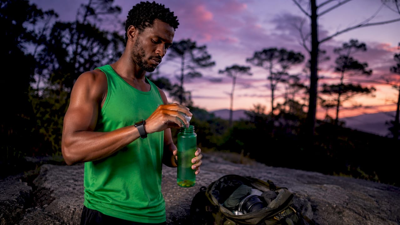 Athlete preparing supplements outdoors by trail