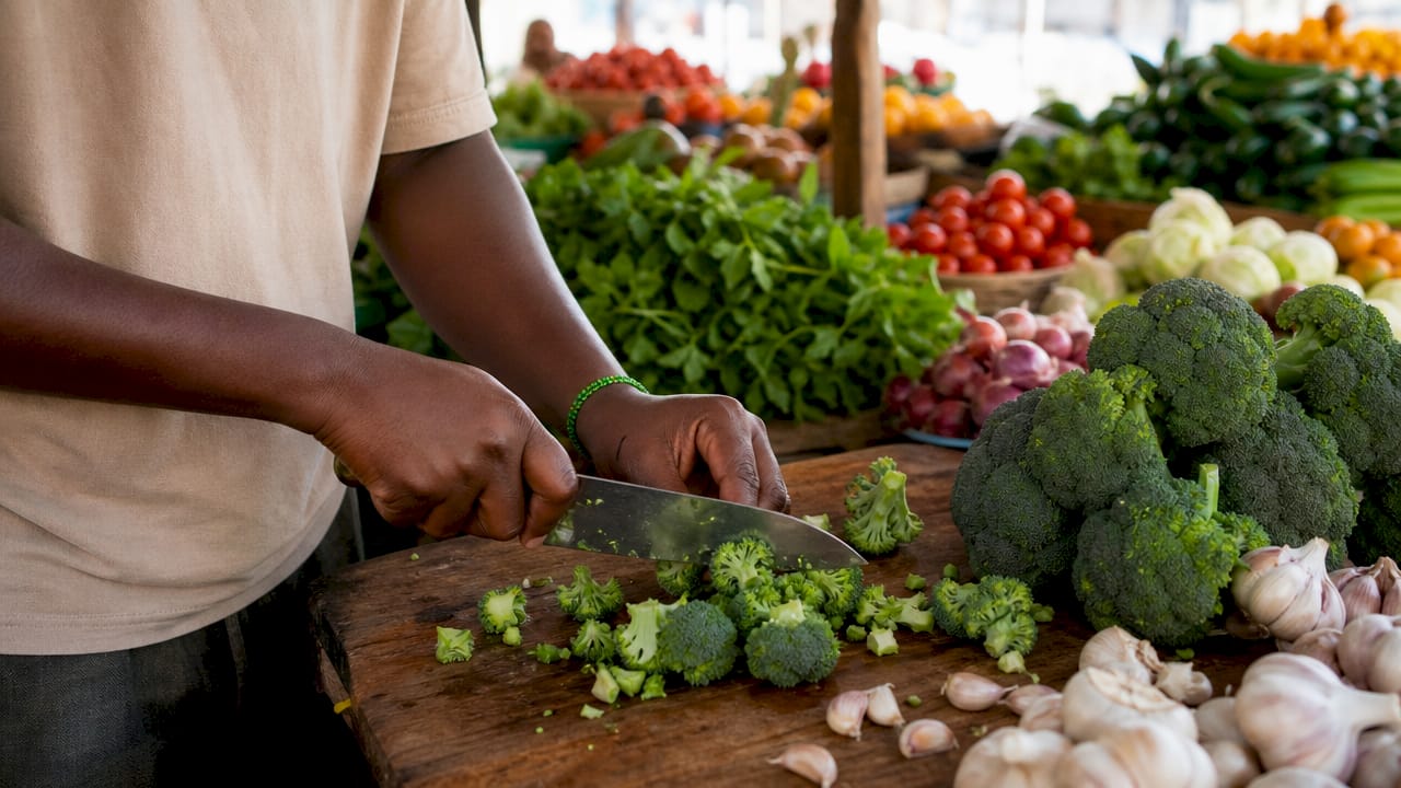 Hands chopping broccoli and garlic in kitchen