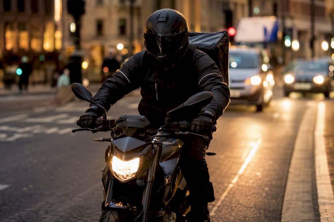 Motorcycle courier riding quickly on city street