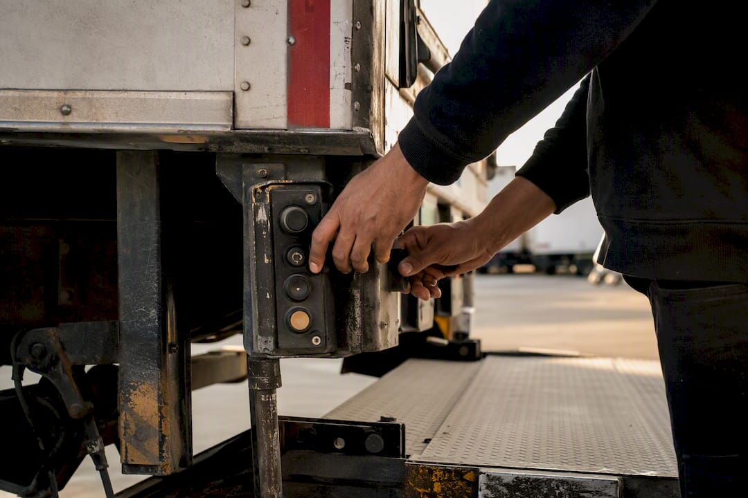 Courier hands operating van tail lift controls