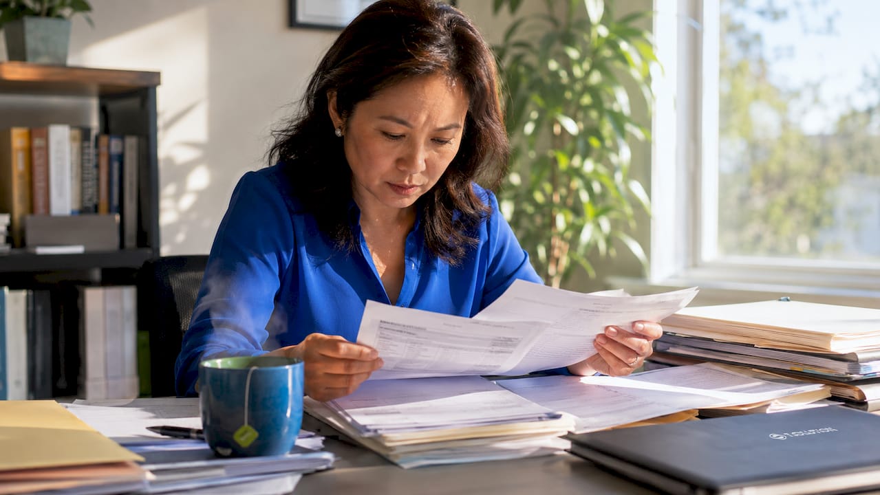 Mortgage processor sorting loan documents at desk