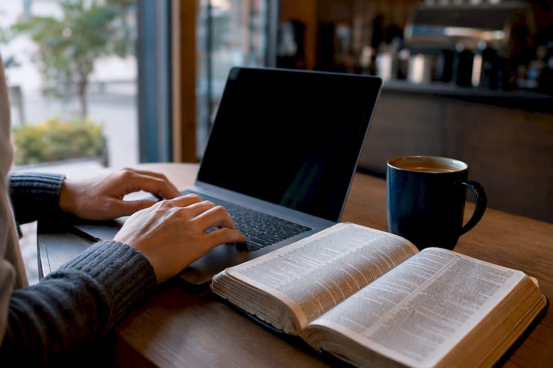 Hands near laptop and open dictionary