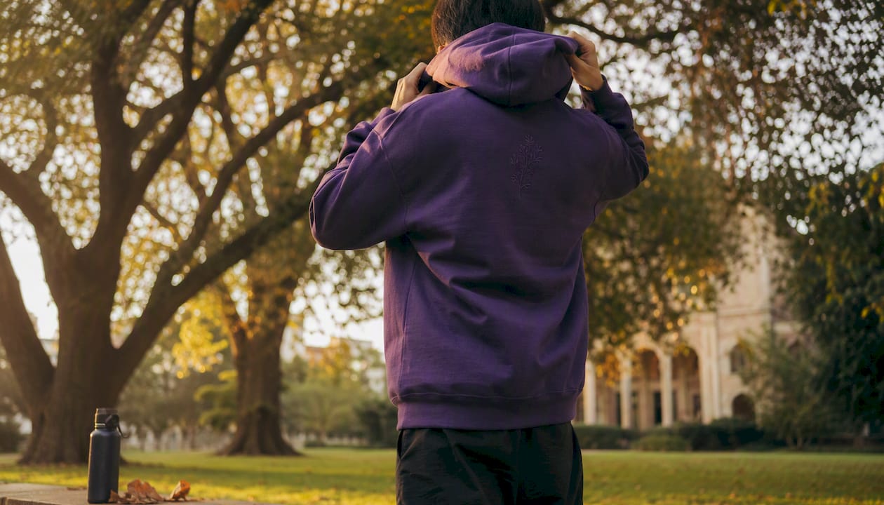 Student adjusting university hoodie outdoors