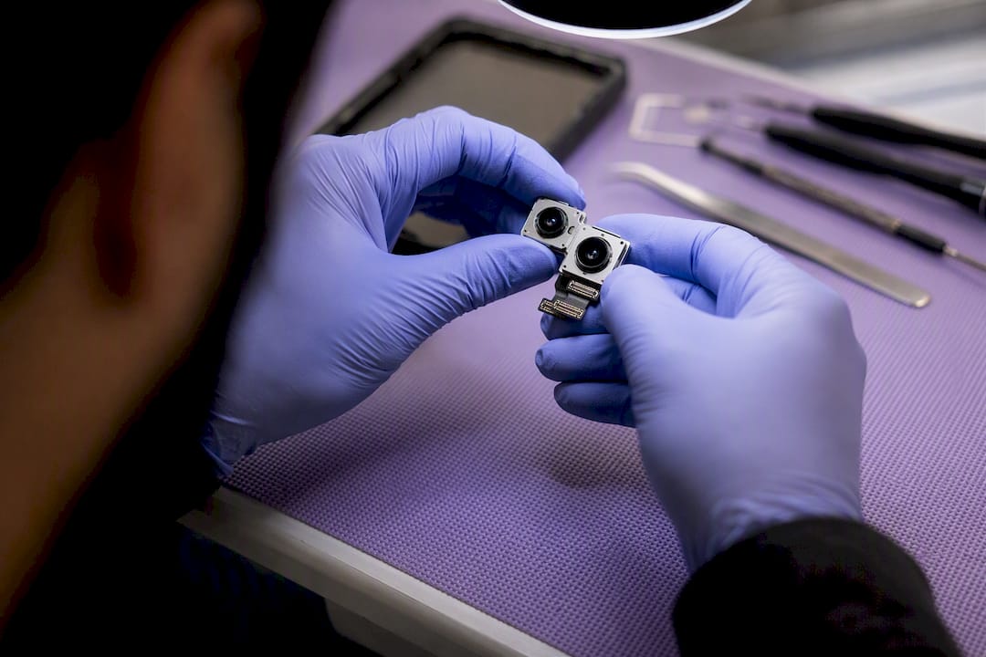 Technician inspecting smartphone camera lens internals