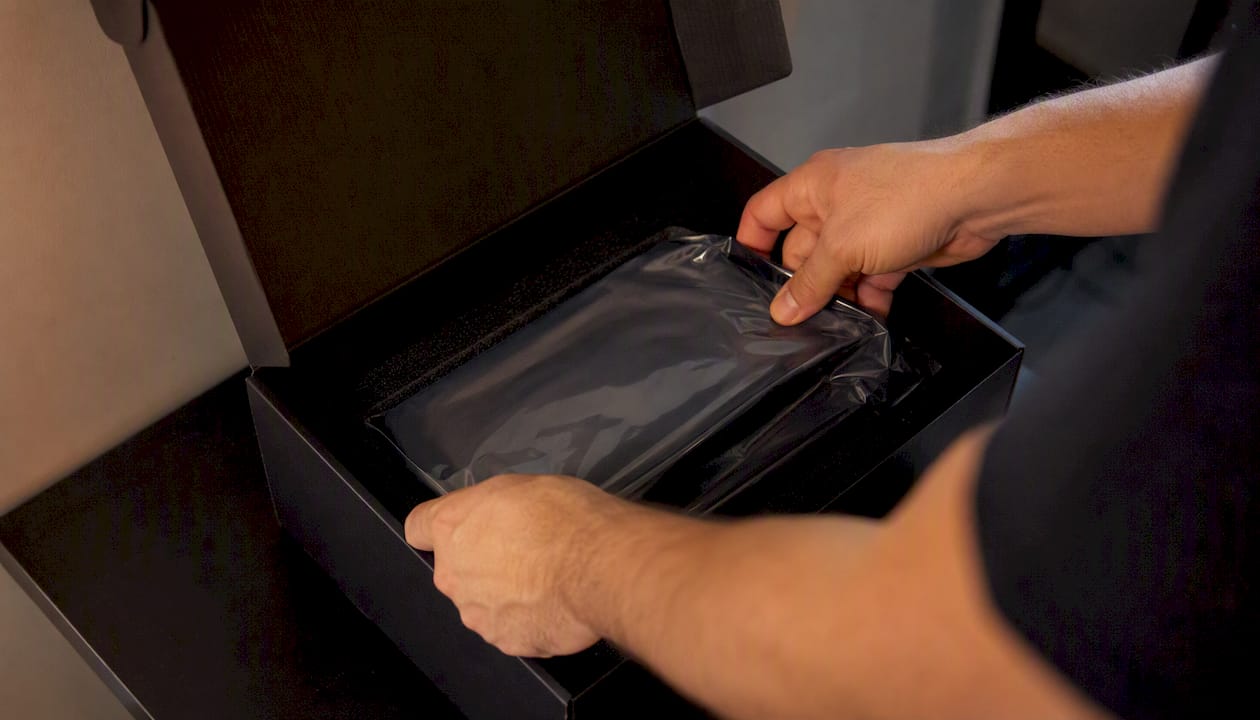 Manos colocando una bolsa al vacío dentro de una caja sencilla.