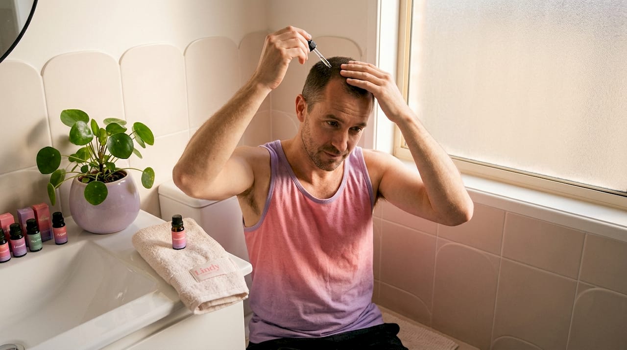 Man applying rosemary oil to scalp at home