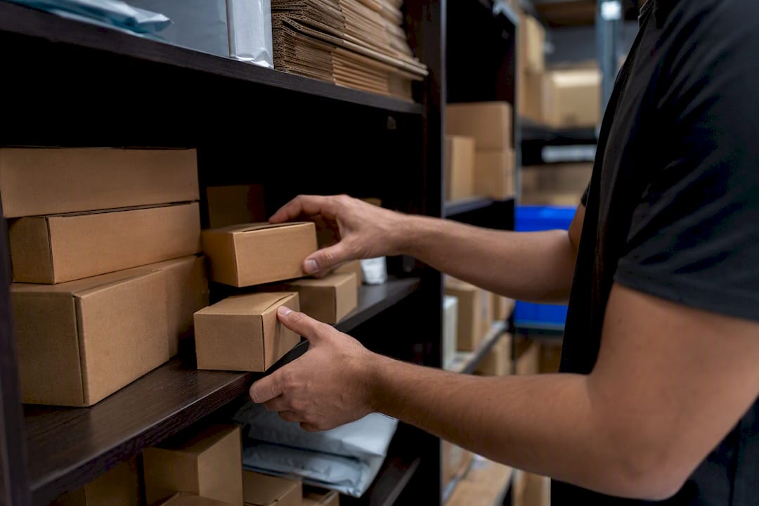 Hands sorting Amazon FBA inventory boxes