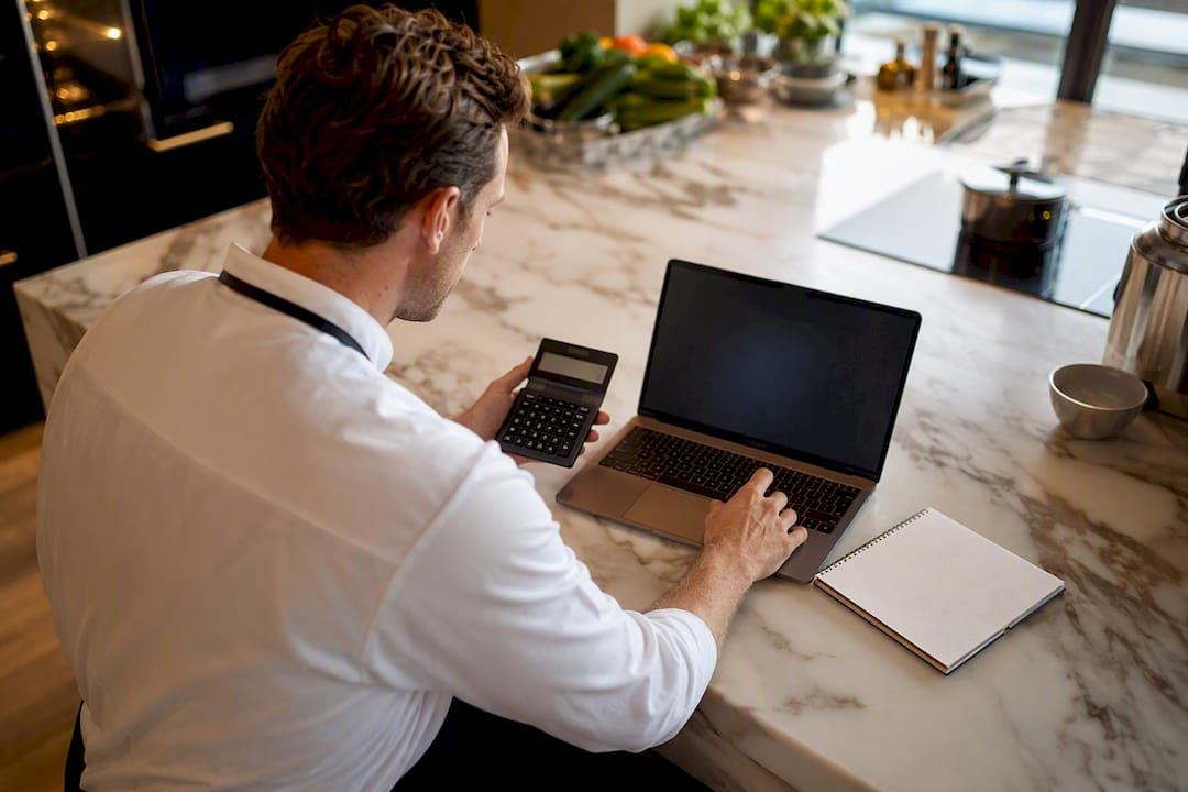 Chef calculating catering costs in kitchen