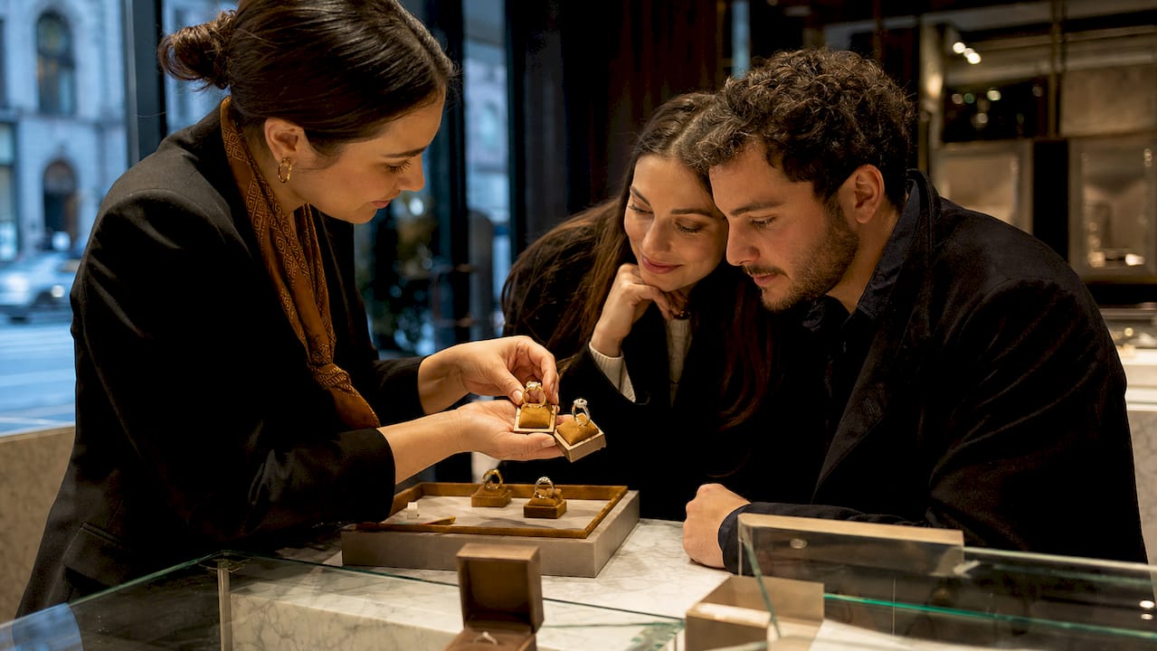 Jeweler showing two-tone rings to couple in store