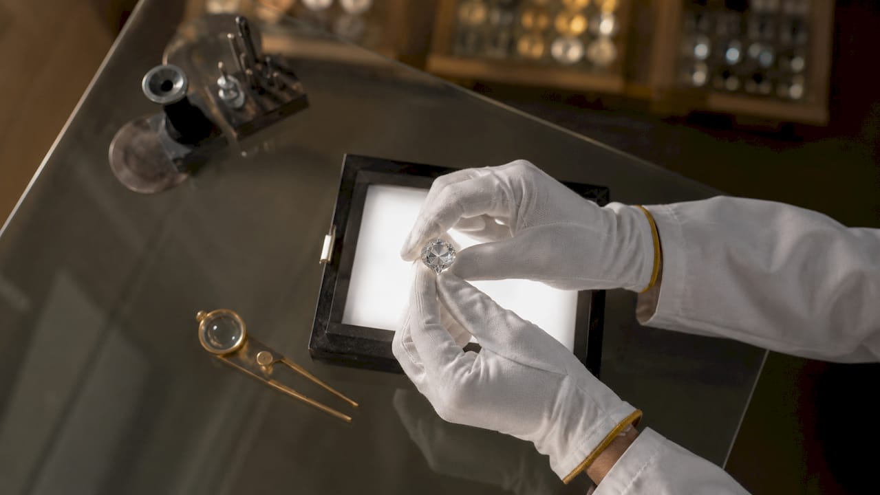 Hands holding diamond over grading light box