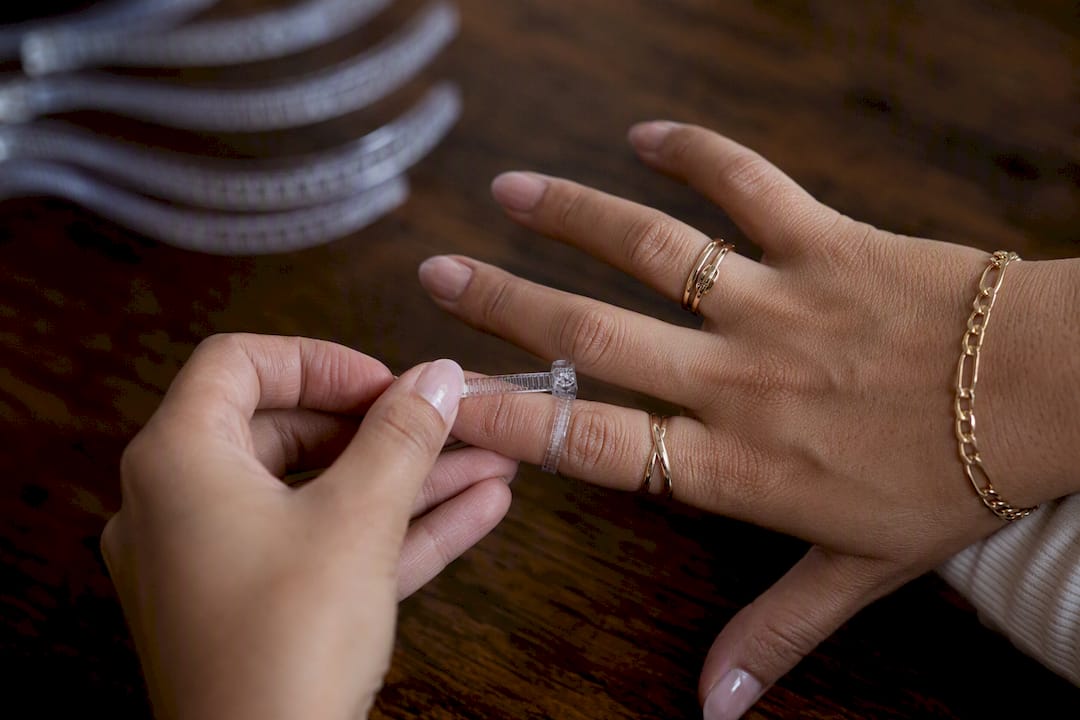 Hand using adjustable plastic ring sizer on finger