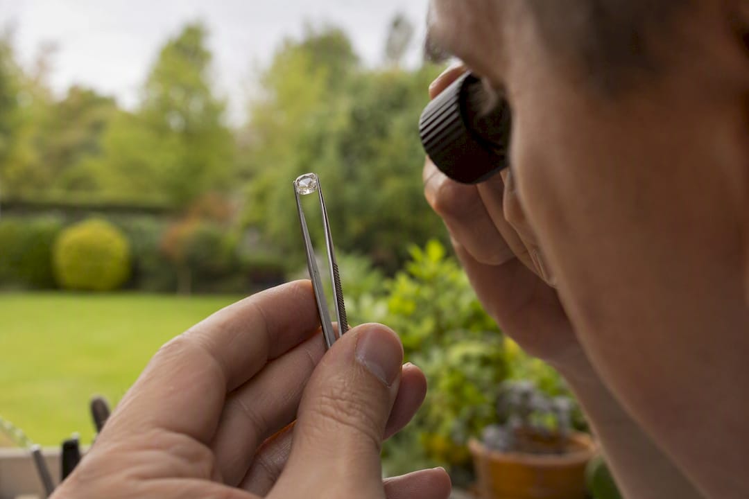 Hand holding diamond under natural light for color inspection