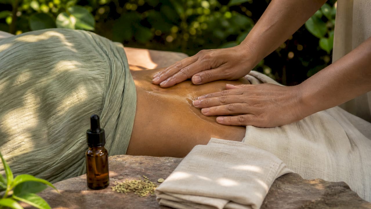 Hands massaging abdomen with fennel oil