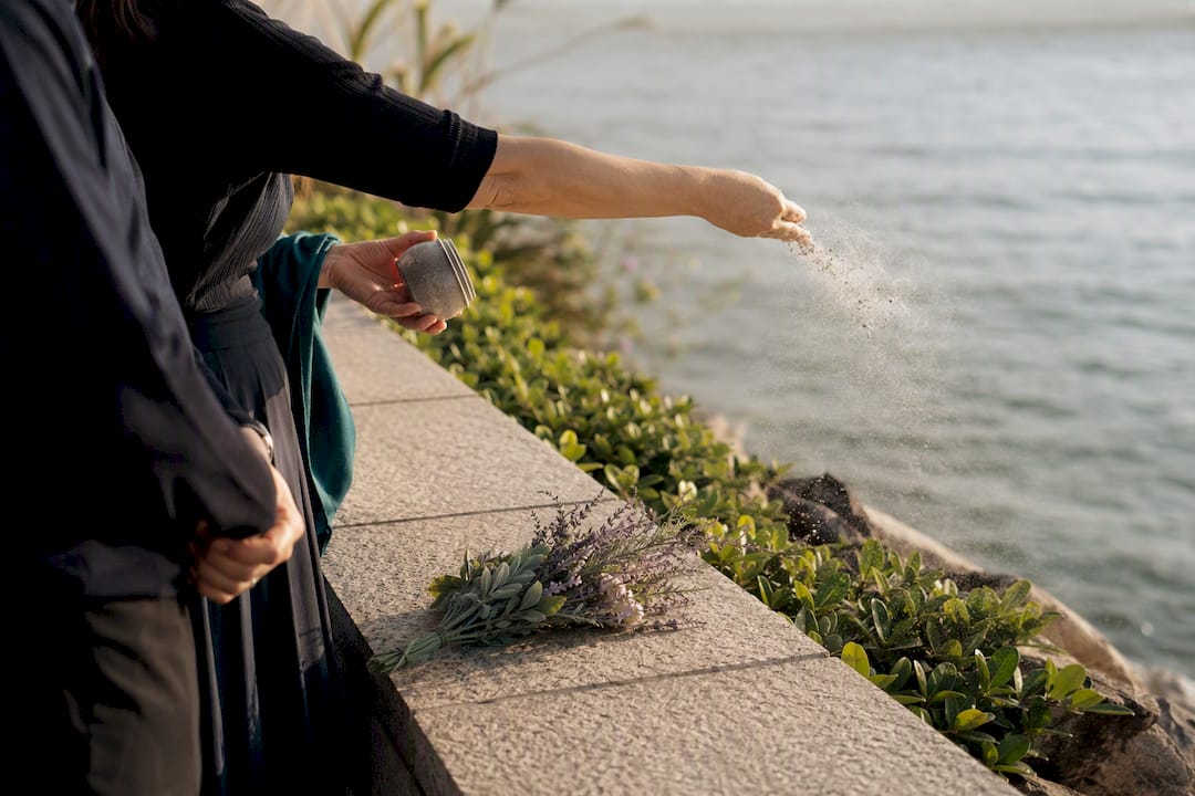 Family scattering ashes at shoreline memorial