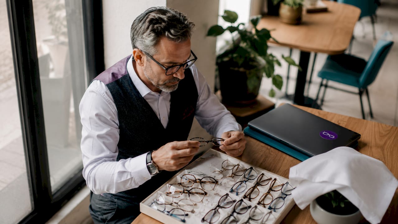 Un bărbat își alege o pereche de rame pentru ochelari progresivi într-un magazin de optică.