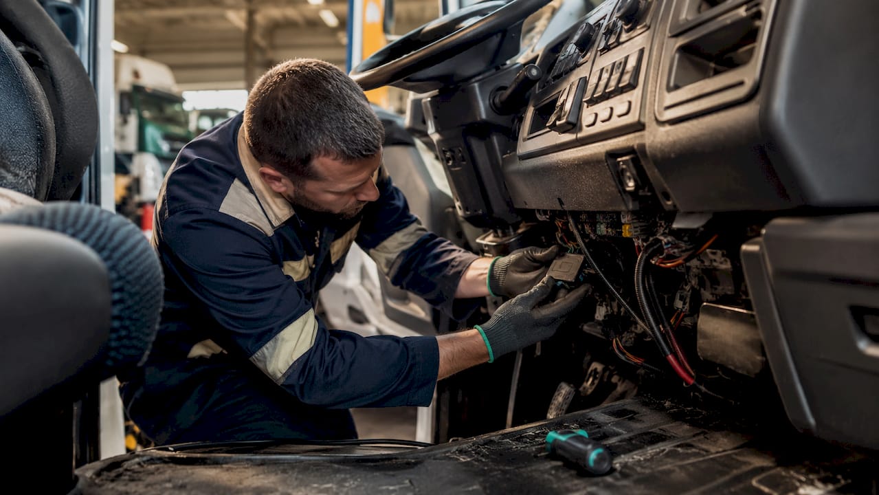 Technician installing rugged telematics device in truck cab