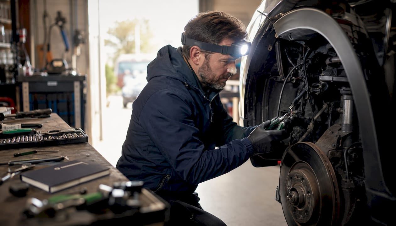 Security expert inspecting vehicle wiring in workshop