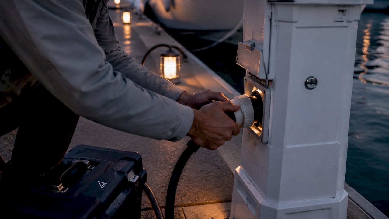 Technician connecting shore power at marina slip