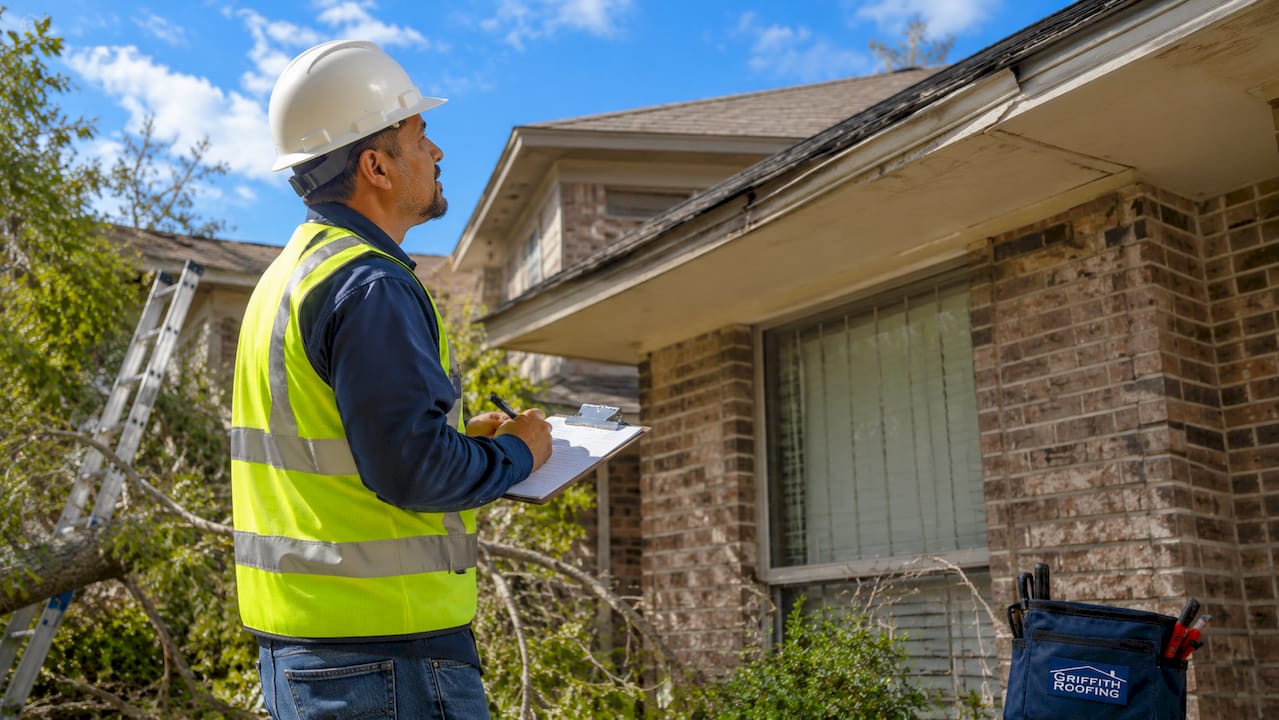 Roofing contractor assessing storm damage on roof