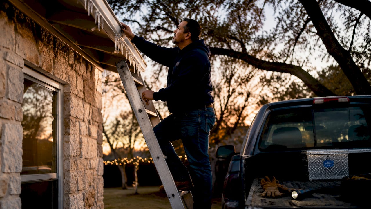 Homeowner inspecting roof ice dam damage