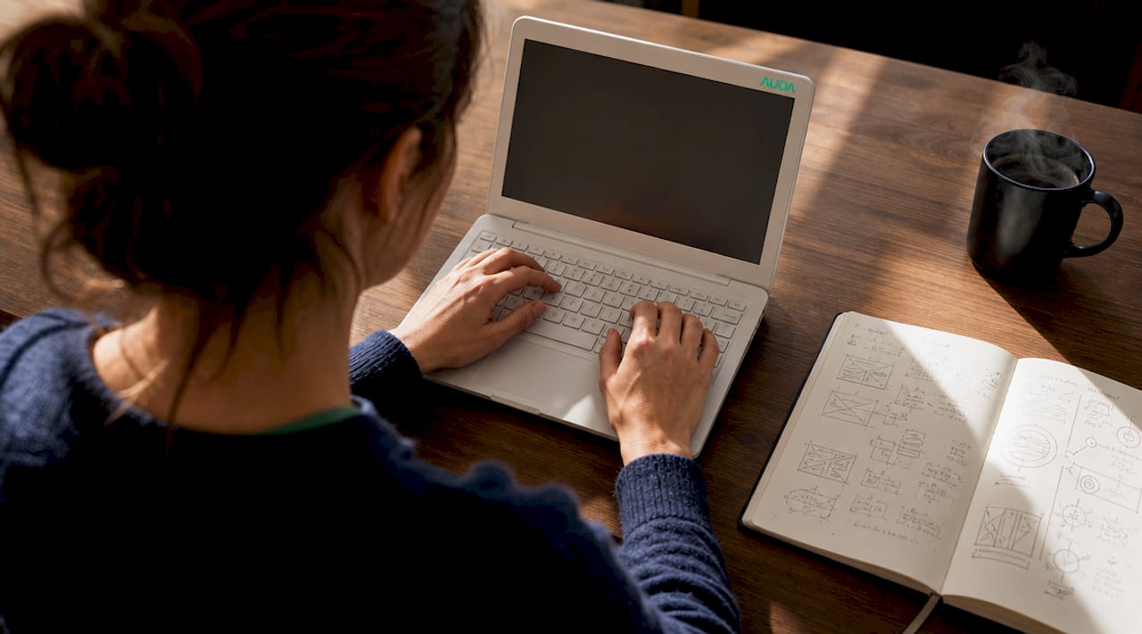 Des mains s’activent sur un clavier, installées dans un bureau à la maison.
