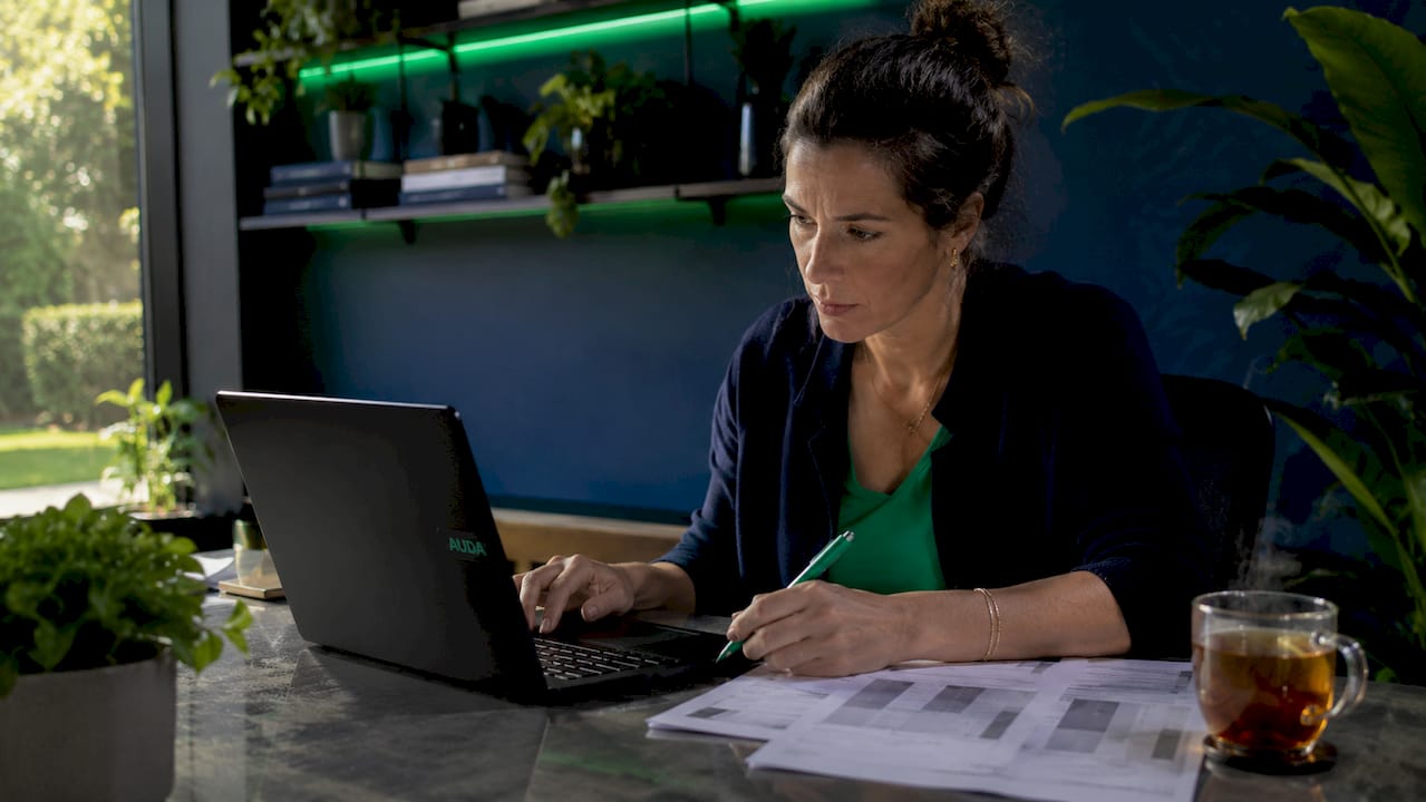 Des mains s’activent sur un clavier d’ordinateur portable, entourées de notes et de pense-bêtes.