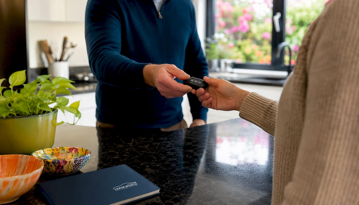Hands exchanging car key over leasing documents