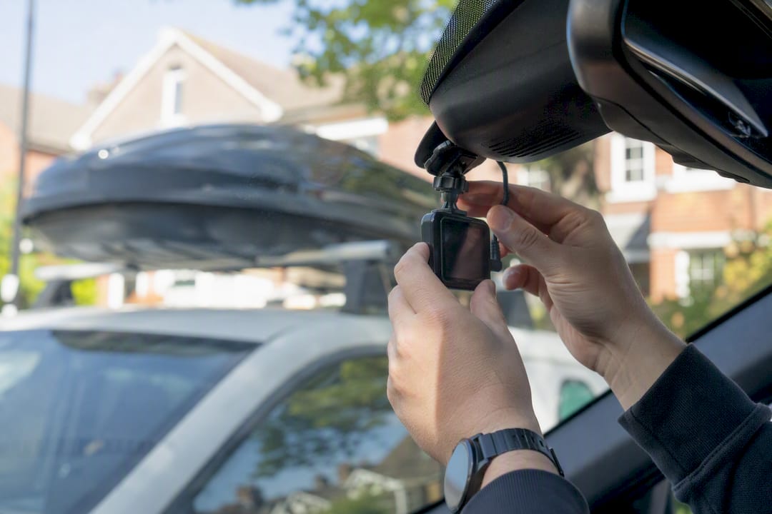 Hands fitting dashcam inside a vehicle