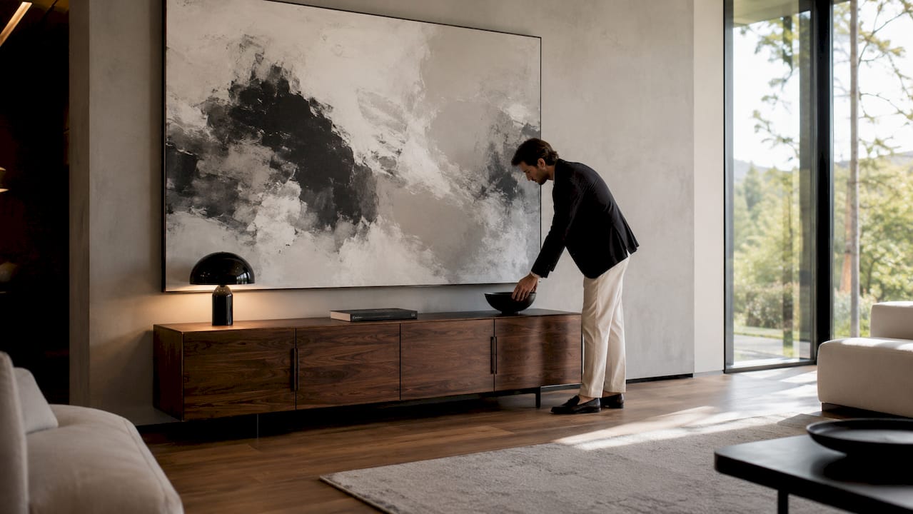 Man arranging vase under large canvas in hallway