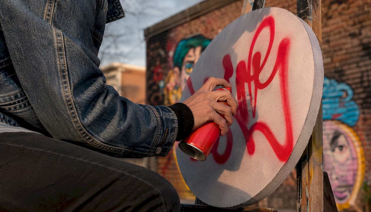 Close-up of hand painting graffiti tag on canvas
