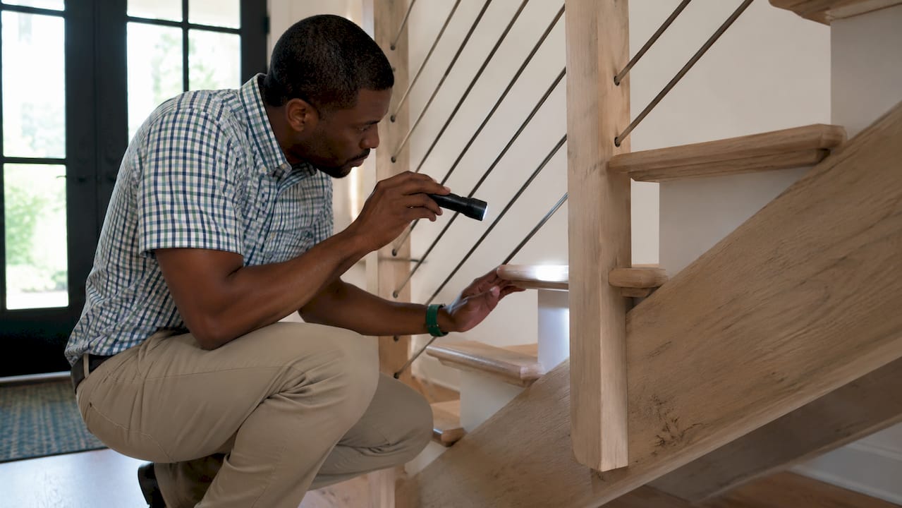 Inspector checking wooden staircase railing integrity