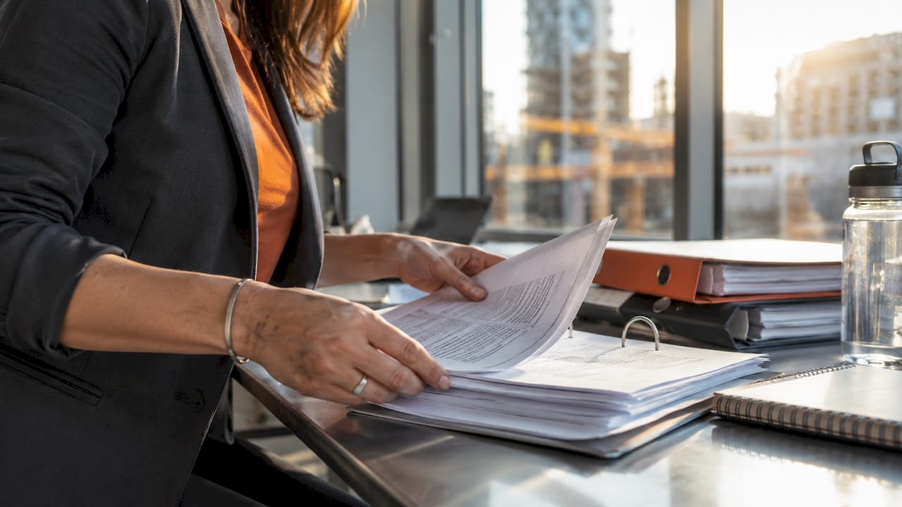 Estimator organizing construction bid documents on table