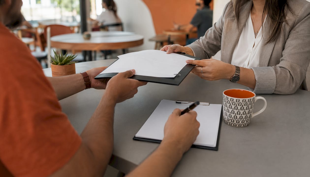 Hands exchanging conditional award contract papers