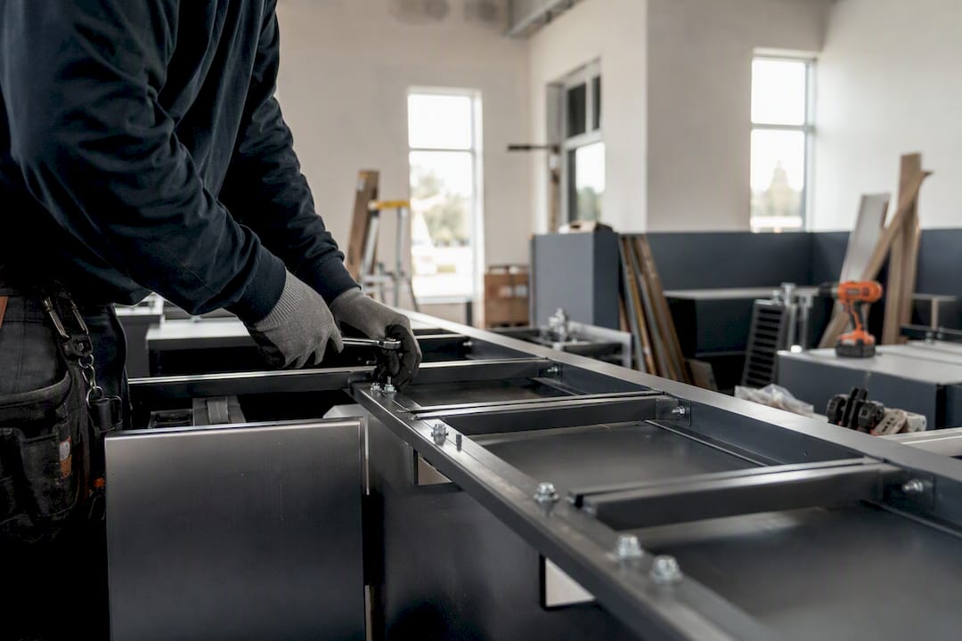 Hands installing metal frame inside postal unit construction site