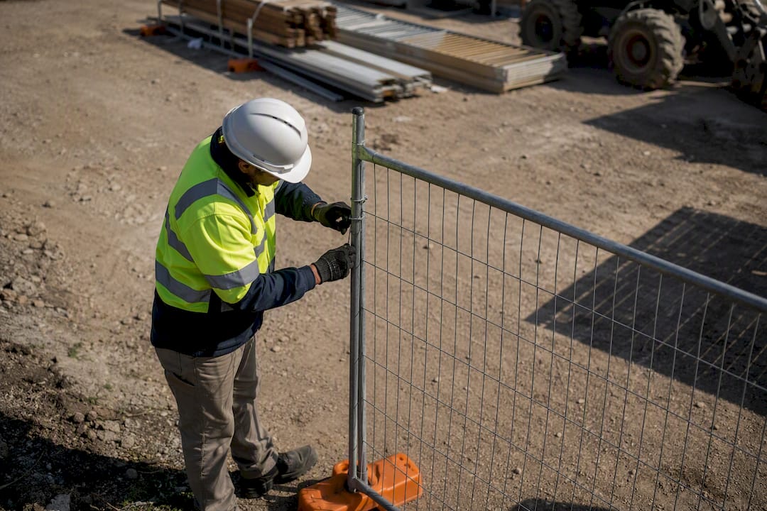 Worker securing safety fence post onsite