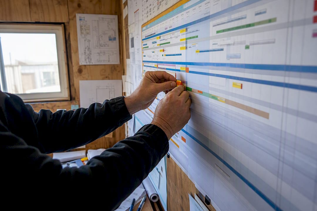 Hands adjusting RACI chart on site trailer wall