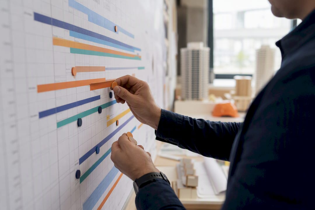 Hands adjusting cost loading schedule on wall chart