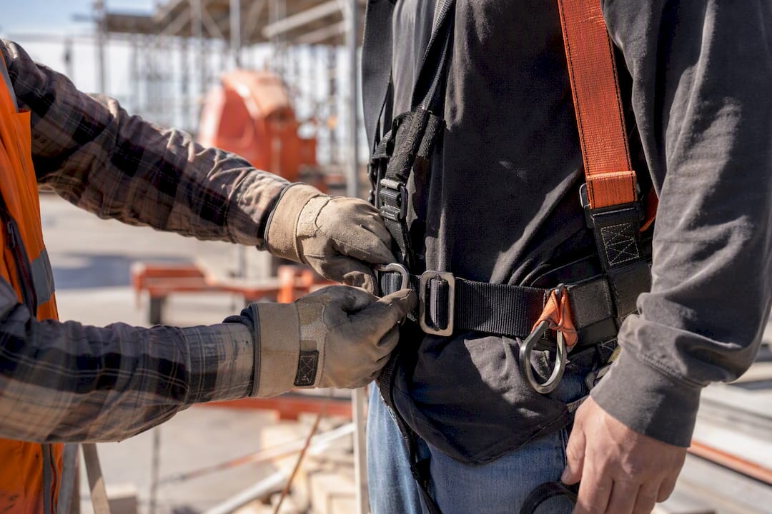 Hand adjusting safety harness on worker