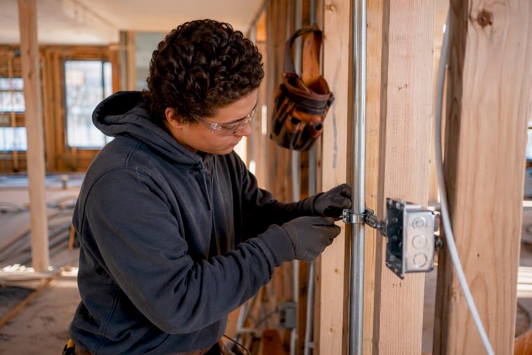 Hands installing electrical conduit on site
