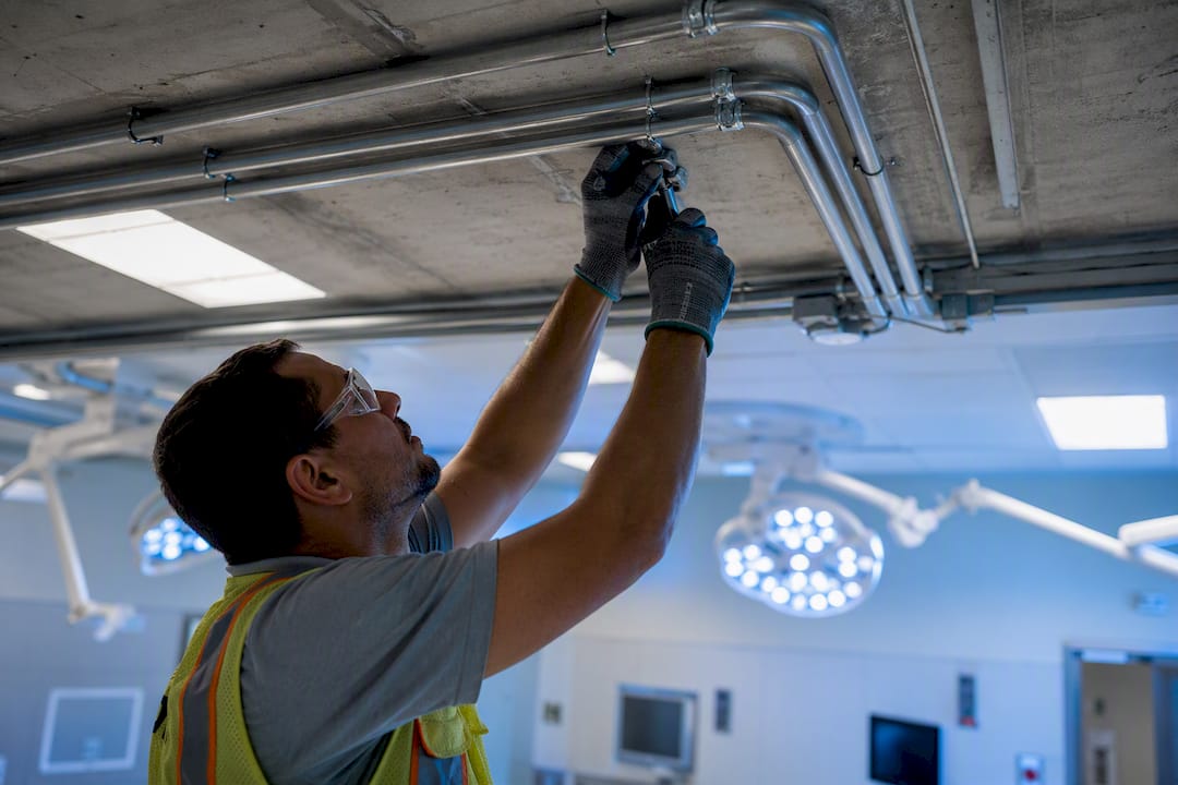 Electrician installing conduit in hospital room ceiling