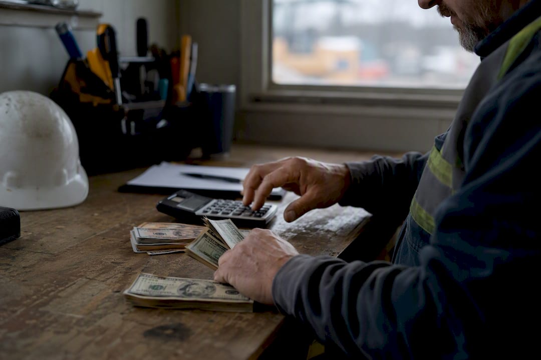 hands counting cash with calculator on site