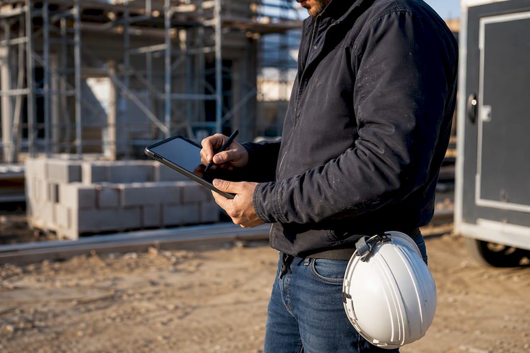 Construction manager recording metrics on tablet outdoors