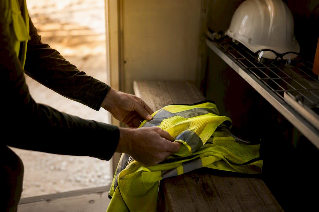 Hands adjusting safety vest inside site trailer