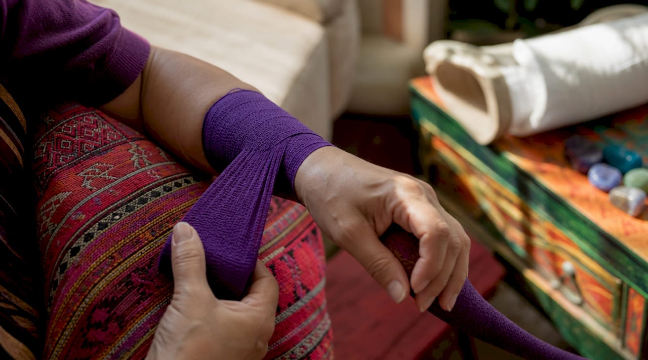 Hands wrapping elastic bandage next to rigid cast